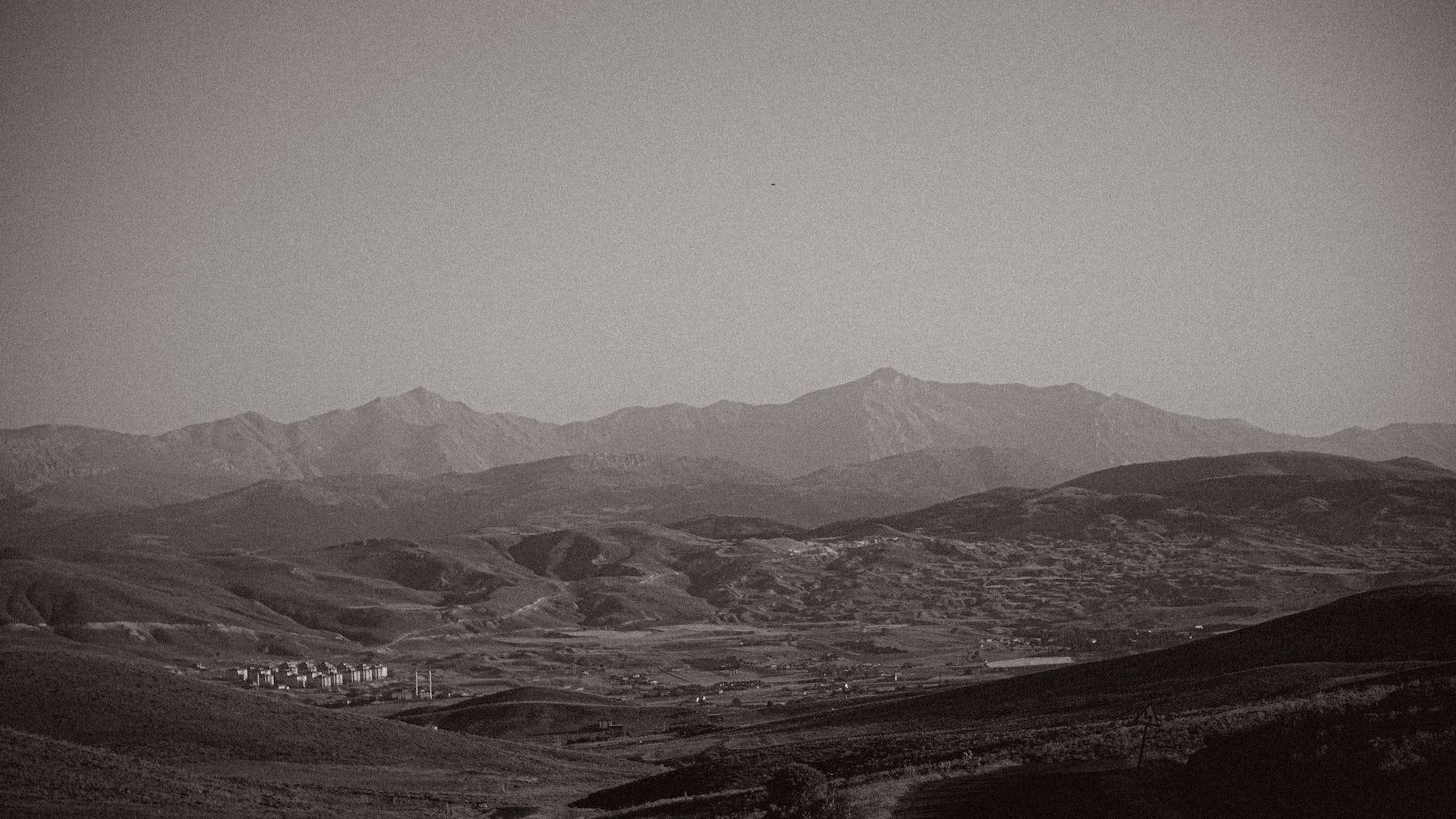 hills on a desert covered with fog in black and white